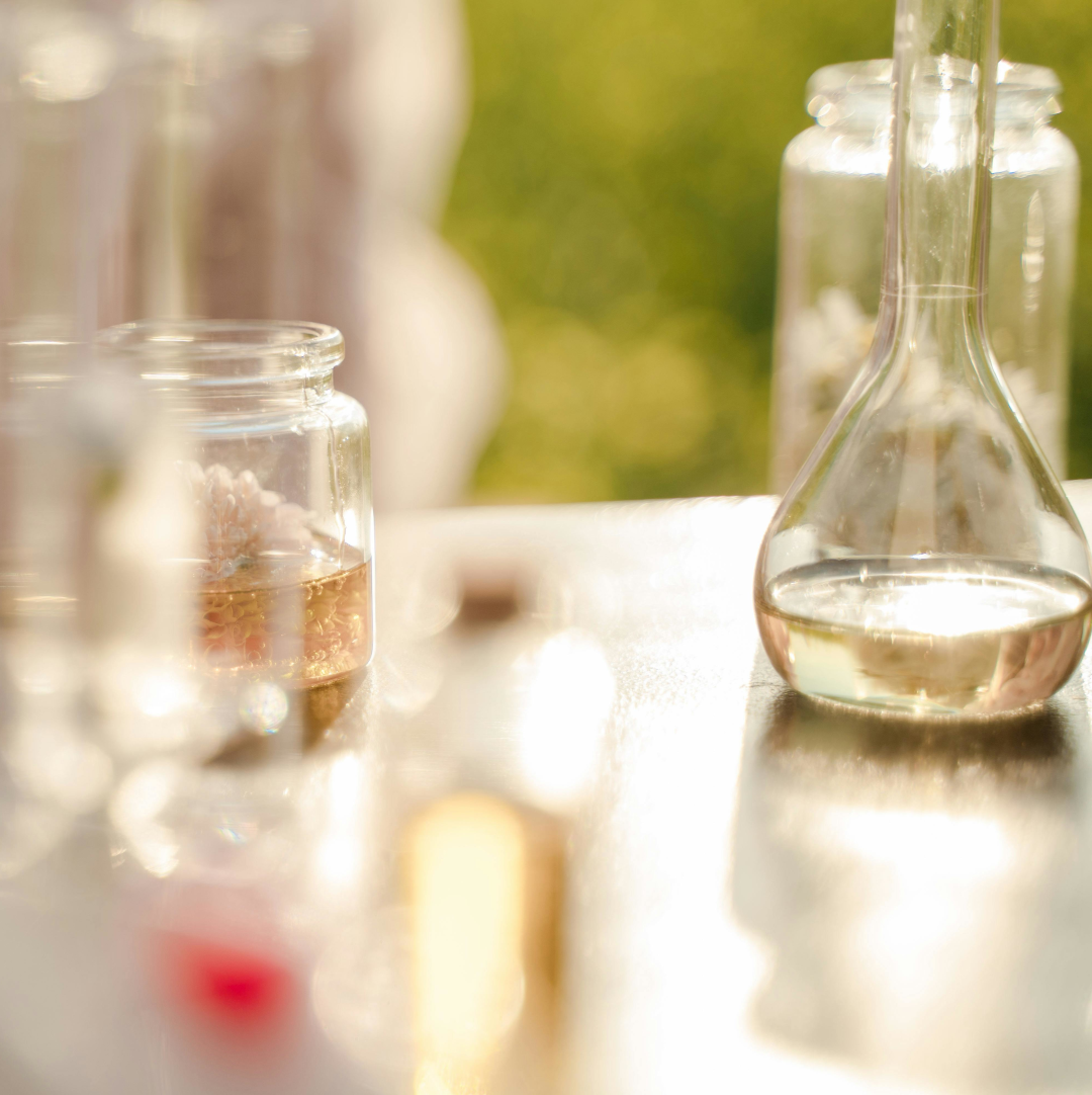 Glass beakers on a table in a sunny, outdoor setting, representing scientific research.